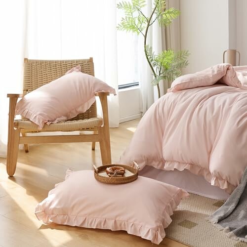 Cozy bedroom with pink bedding and pillows on a chair.