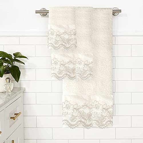 Elegant white towels with lace trim hanging in a bathroom.