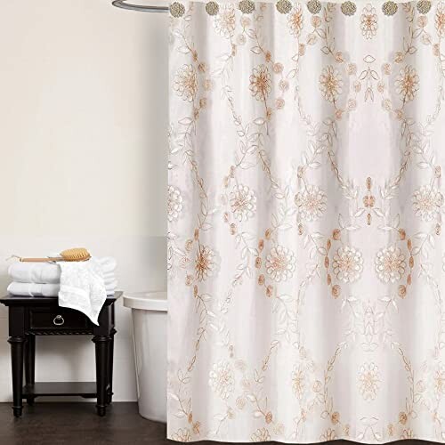 Bathroom with floral shower curtain and small table.