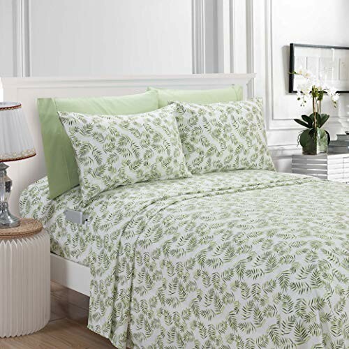 Bedroom with green leaf pattern bedding set and decorative pillows.