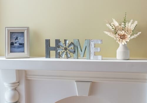 Mantelpiece with 'HOME' letters, vase with flowers, and framed photo.