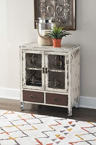 Vintage cabinet with decorative items on top, including a plant and a metal vase.