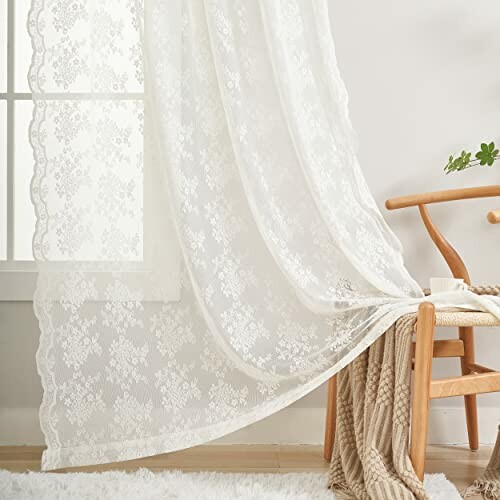 White lace curtains hanging beside a wooden chair with a knitted blanket.