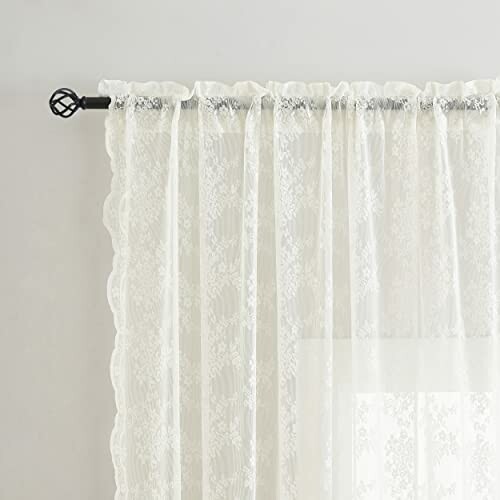 White sheer lace curtain hanging on a rod.